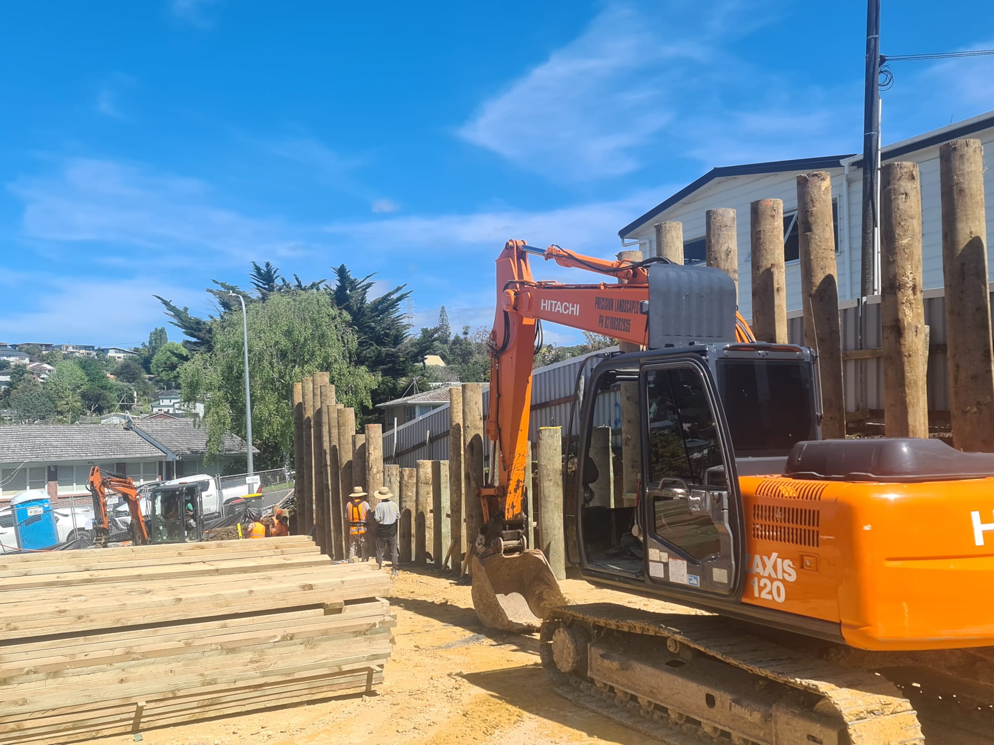 Excavator working beside timber retaining materials